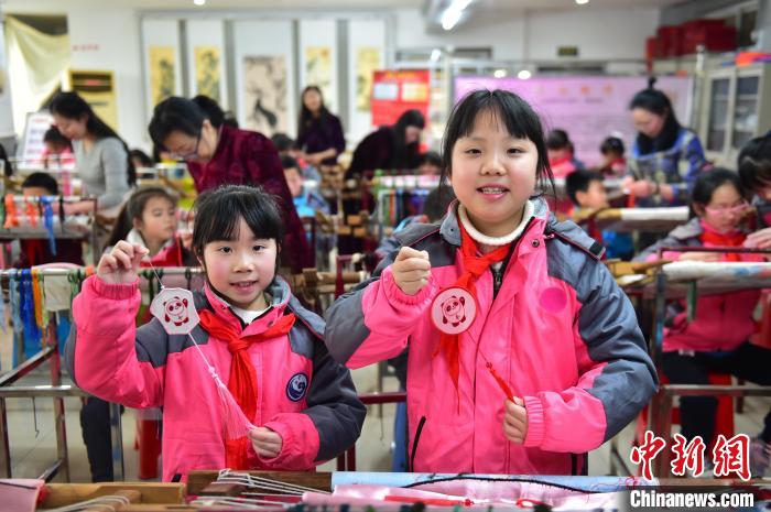 圖為小學(xué)生展示繡制好的2022年北京冬奧會(huì)吉祥物“冰墩墩”形象。　喻云亮 攝