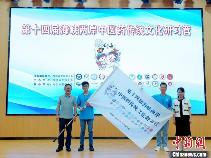 共青團(tuán)福建省委副書記吳雪(右一)、福建中醫(yī)藥大學(xué)黨委副書記林羽(左一)為兩岸學(xué)生代表頒授營旗?！≡S燁婷 攝