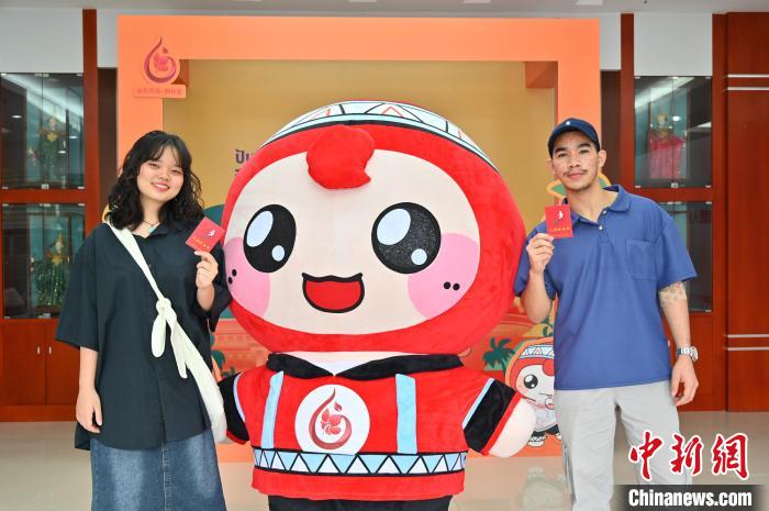 圖為泰國(guó)留學(xué)生手持獻(xiàn)血證與人偶合影?！∮峋?攝