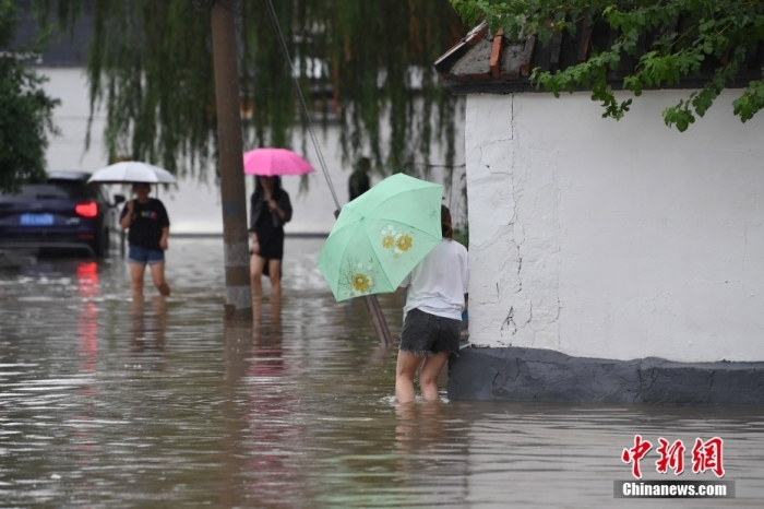 7月31日，市民行走在雨中的北京房山區(qū)瓦窯頭村。北京市氣象臺當(dāng)日10時(shí)發(fā)布分區(qū)域暴雨紅色預(yù)警信號。北京市水文總站發(fā)布洪水紅色預(yù)警，預(yù)計(jì)當(dāng)日12時(shí)至14時(shí)，房山區(qū)大石河流域?qū)⒊霈F(xiàn)紅色預(yù)警標(biāo)準(zhǔn)洪水。<a target='_blank' href='/'><p  align=