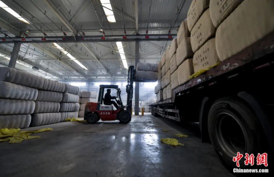 新疆喀什綜合保稅區(qū)，喀什啟路國(guó)際貿(mào)易有限公司的倉庫內(nèi)，工人正在裝載從塔吉克斯坦和烏茲別克斯坦進(jìn)口的棉花。劉新攝