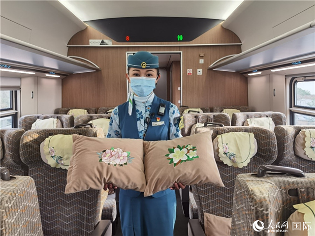 趙瑩靜展示中老鐵路國際旅客列車里帶有中國牡丹花和老撾占巴花刺繡圖案的靠墊。人民網(wǎng)記者 杜明明攝