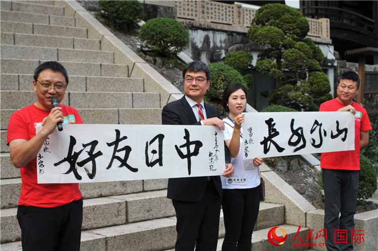 東京中國文化中心主任羅玉泉展示其為本次活動書寫的題詞“中日友好，山高水長”。人民網 蔣曉辰攝