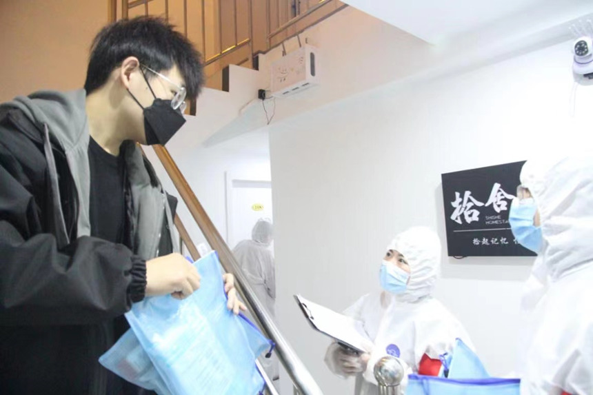 社區(qū)工作人員和志愿者身穿防護服上門送馬應龍大健康防疫包。徐帥攝