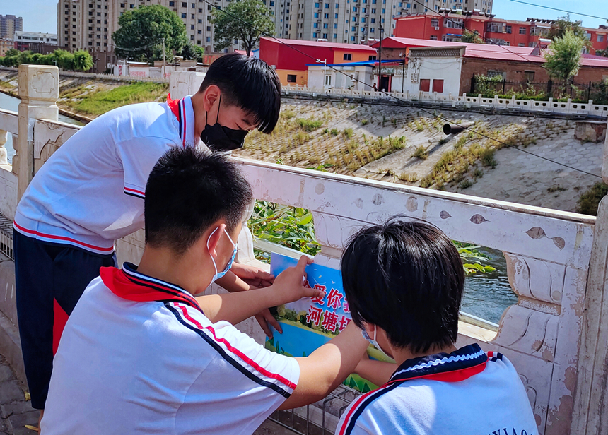 徐水小學(xué)學(xué)雷鋒志愿者在瀑河河邊張貼防溺水警示標(biāo)語(yǔ)。 徐水區(qū)委宣傳部供圖