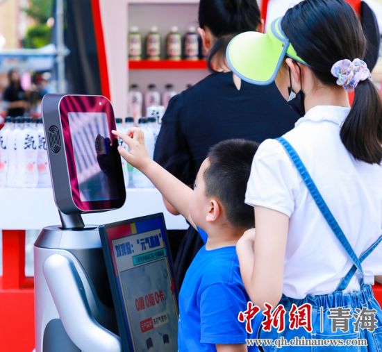 圖為一名小朋友正在和機(jī)器人“志愿者”進(jìn)行互動(dòng)。 沐聞 攝