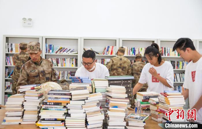 圖為志愿者們和邊防戰(zhàn)士整理圖書。　劉曉東 攝