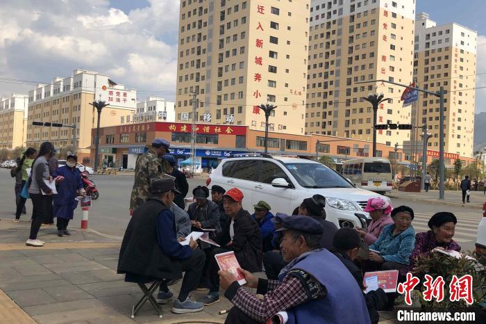 圖為會(huì)澤縣城易地扶貧搬遷安置點(diǎn)內(nèi)，老人們聚在廣場(chǎng)上聊天，身后是他們的新家。　繆超 攝