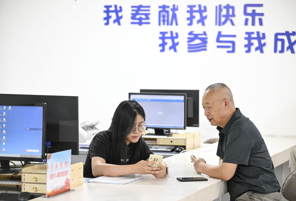 2024年6月20日，在寧夏銀川市金鳳區(qū)長城花園社區(qū)黨群服務(wù)中心，工作人員幫助居民辦理業(yè)務(wù)。圖片來源 新華社