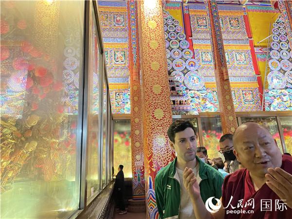 7月25日，省級非物質(zhì)文化遺產(chǎn)項目塔爾寺酥油花的代表性傳承人朋措堅參（右）在塔爾寺酥油花館講解酥油花的制作過程。人民網(wǎng) 謝瑩攝