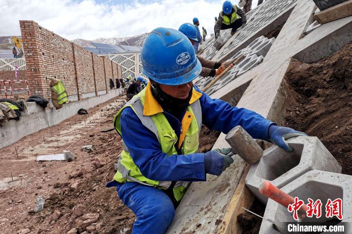 圖為光伏發(fā)電項(xiàng)目施工區(qū)工人在護(hù)坡鋪設(shè)空心磚?！±铍h 攝