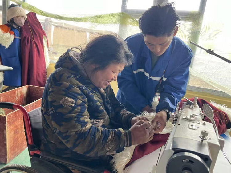 扎西奪爾登幫助殘疾員工裁剪。阿壩州文明辦供圖