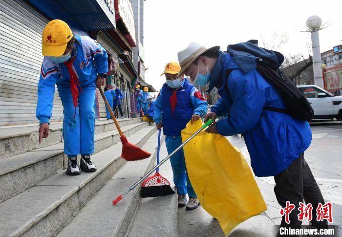 圖為拉薩市小學(xué)生打掃街道?！∝暩聛?lái)松 攝