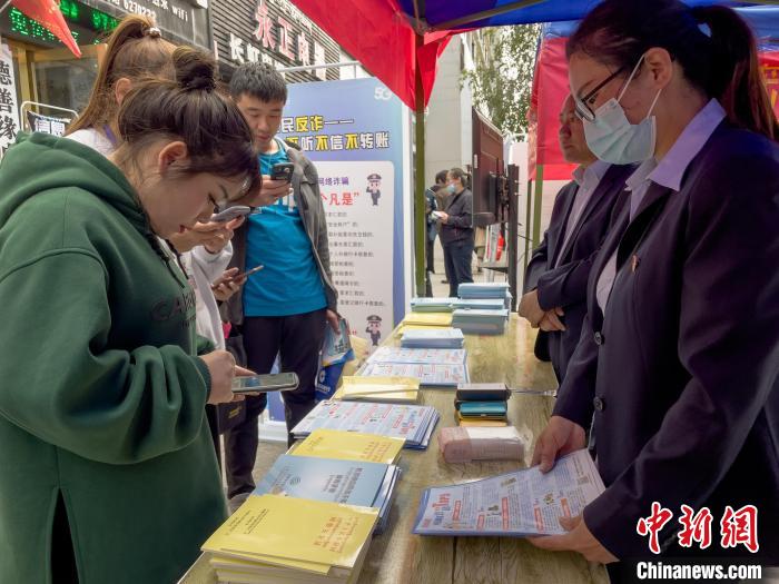圖為工作人員正在向路過(guò)市民介紹國(guó)家反詐中心軟件的功能?！≈x牧 攝