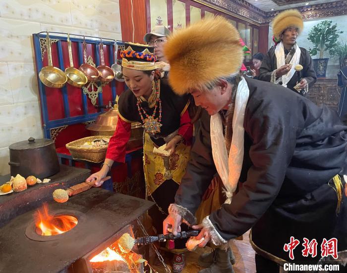 圖為人們在火上烤節(jié)日美食“結(jié)達(dá)”?！∪轿木?攝