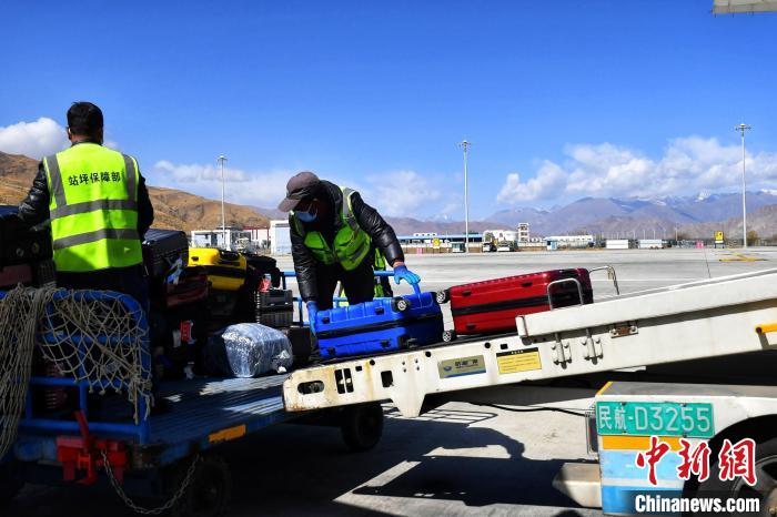 圖為機場工作人員傳送旅客行李箱?！≈芎?攝